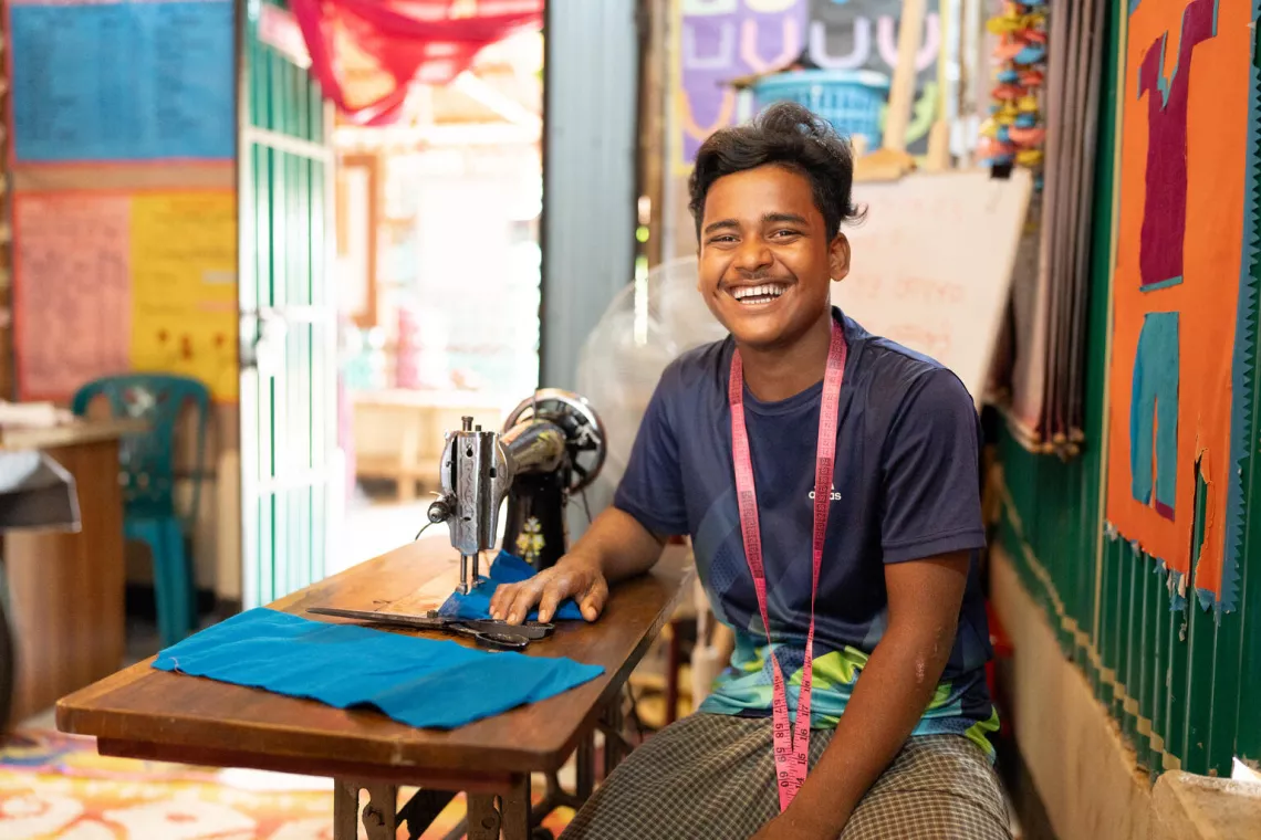 Bangladesh. Nur Kalam, 16, laughs as he takes a break from sewing at a tailoring workshop at a Multi-Purpose Centre.