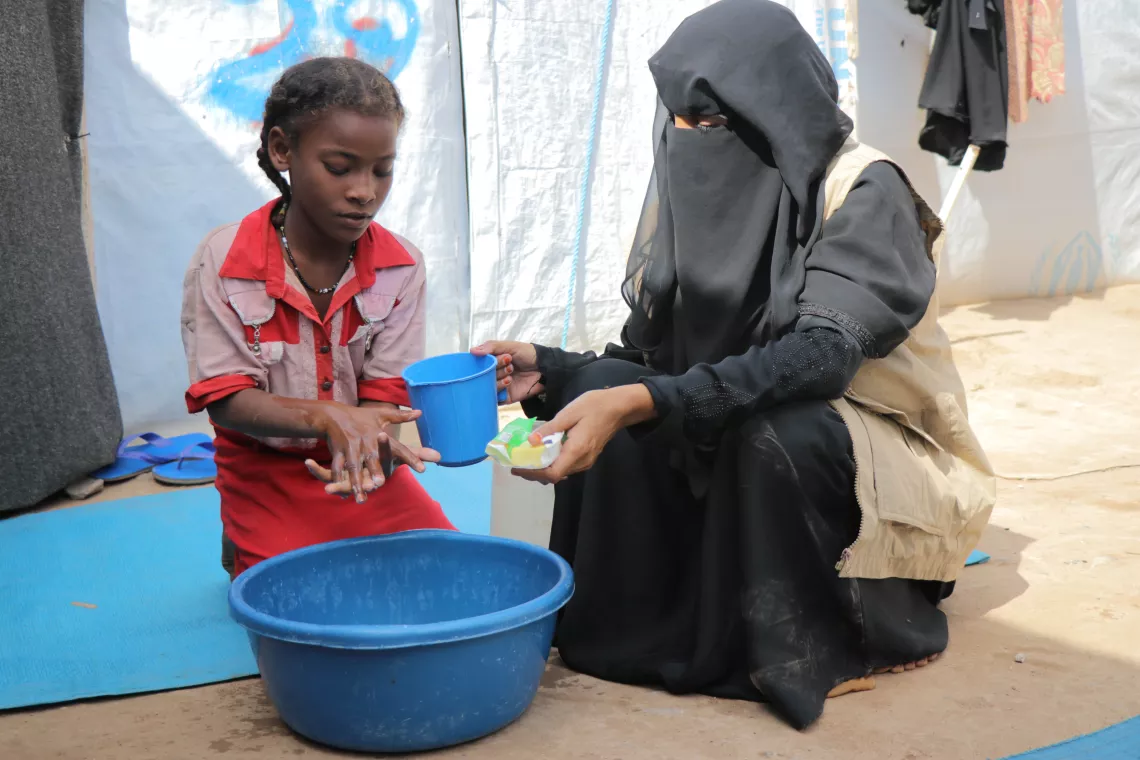 Una educadora capacitada enseña a una niña a lavarse las manos correctamente, en un centro de acogida para familias que huyen de la inestabilidad en el Yemen. 