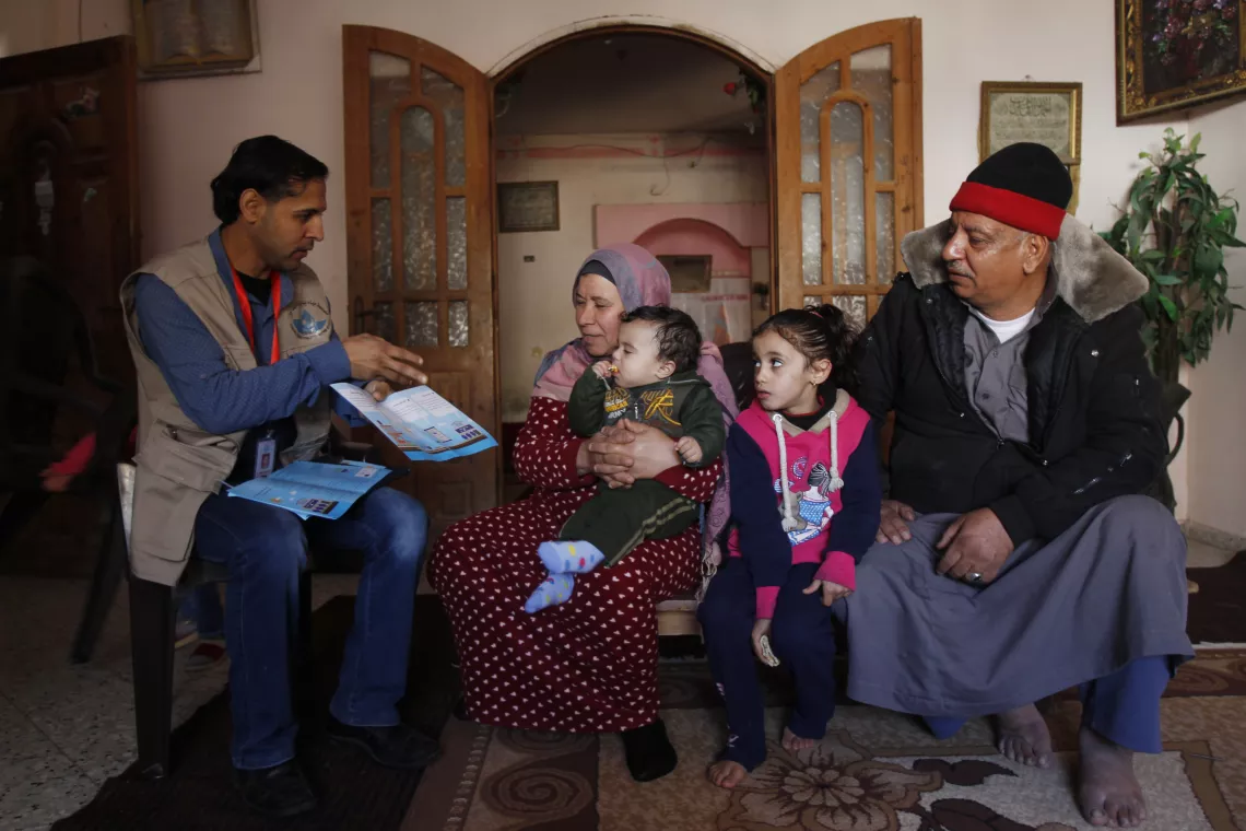 A Palestinian family listen to a member of Gaza’s Coastal Municipalities Water Utility team