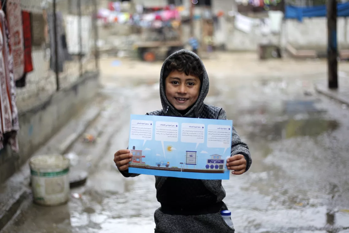 A Palestinian child holds up an information leaflet detailing how desalination works