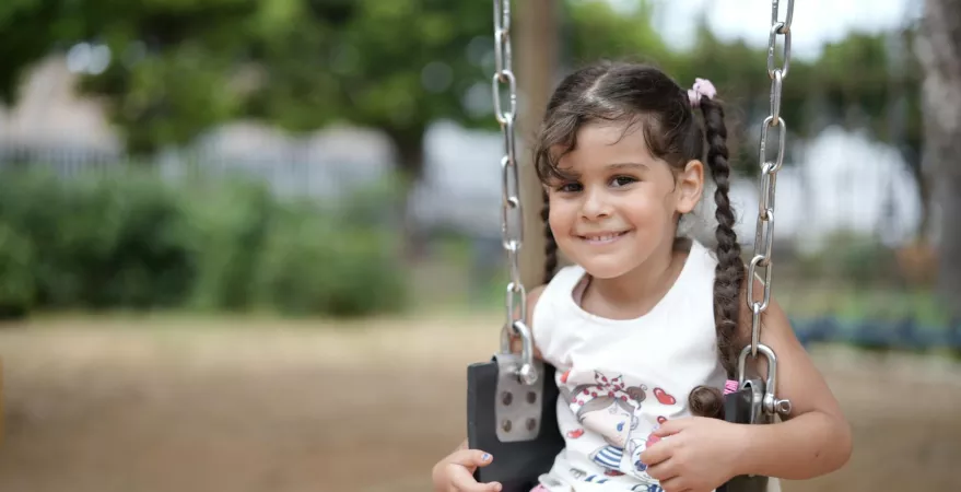 A girl smiles while on a swing