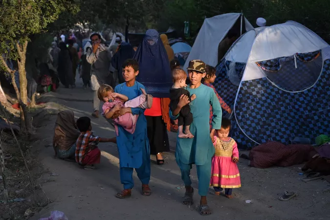 Afghanistan. Internally displaced families walk past temporary tents in Kabul.