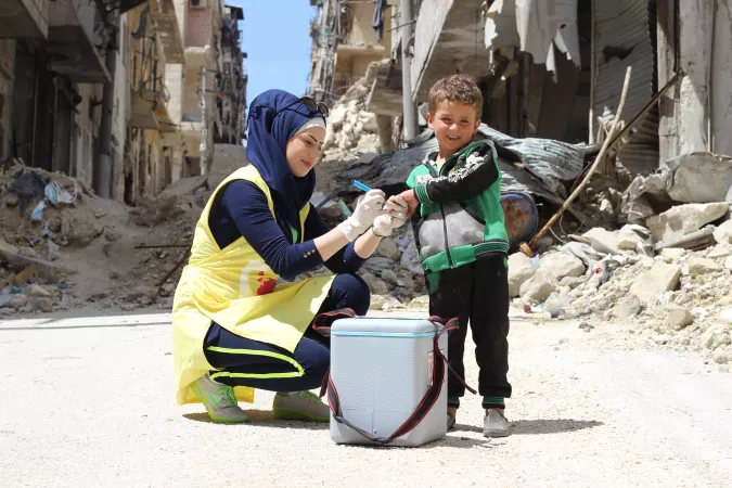 A woman vaccinates a child, Syria