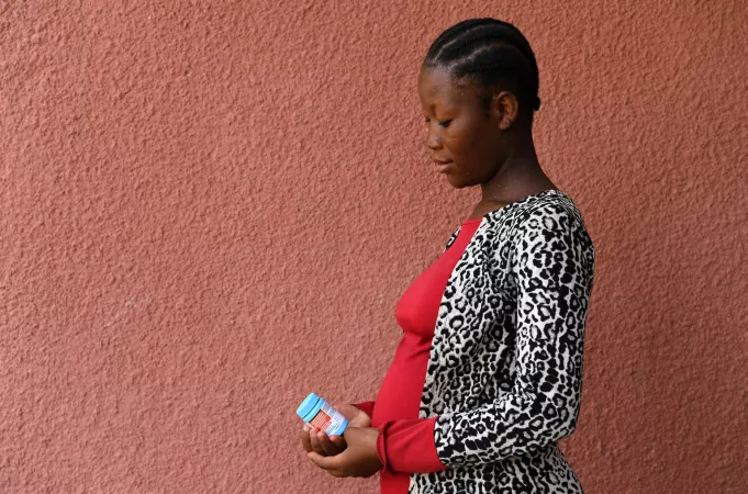A pregnant woman holds a bottle of medication.