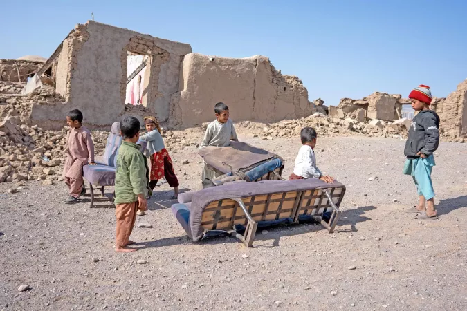 Children collect furniture from their destroyed homes.