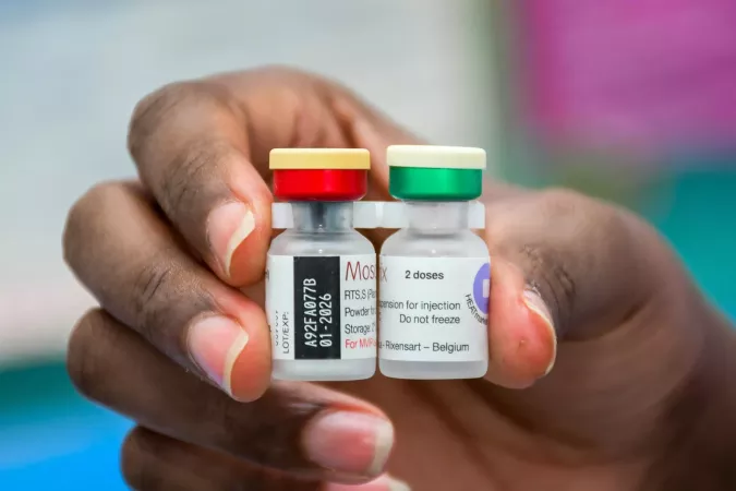 A  hand holds two vaccine viles.