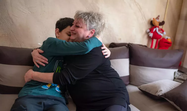 A foster mother hugs her adopted teenage son.