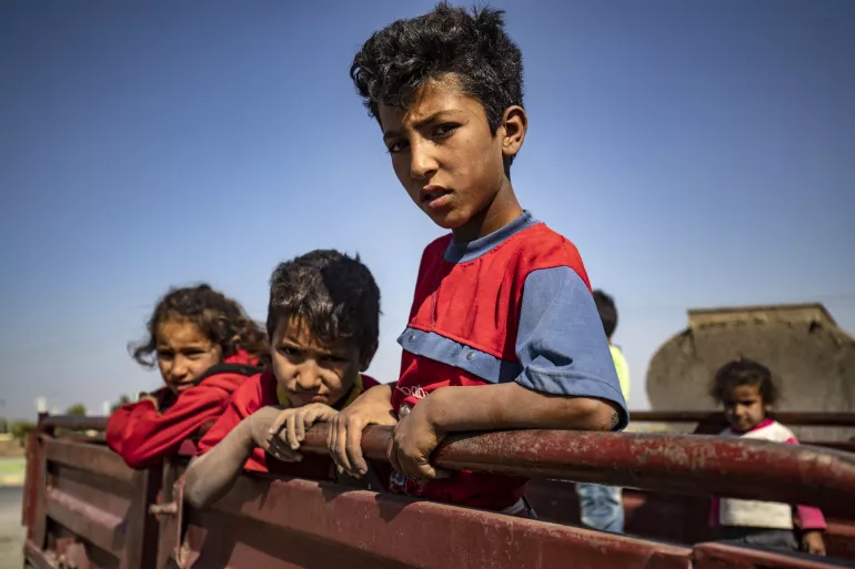 Syria. Children stand on the back of a truck.