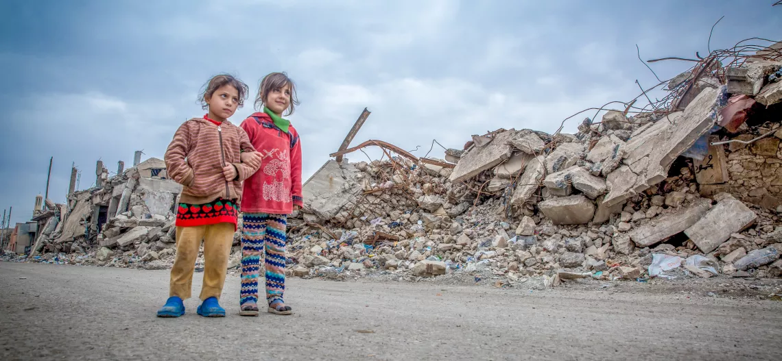 طفلان يسيران حيث تم تدمير العديد من المباني بالكامل - الموصل ، العراق.