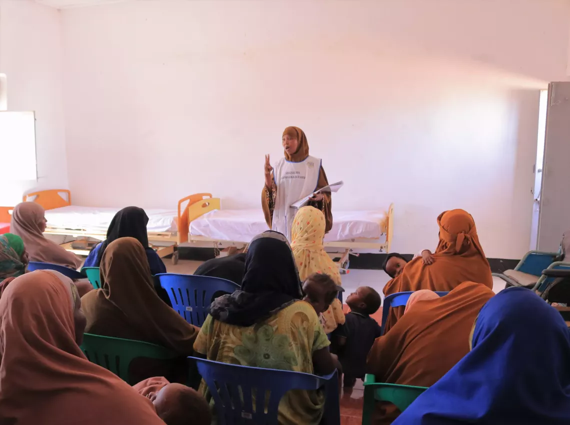 Hawa conducting an information session with a group of mothers. 