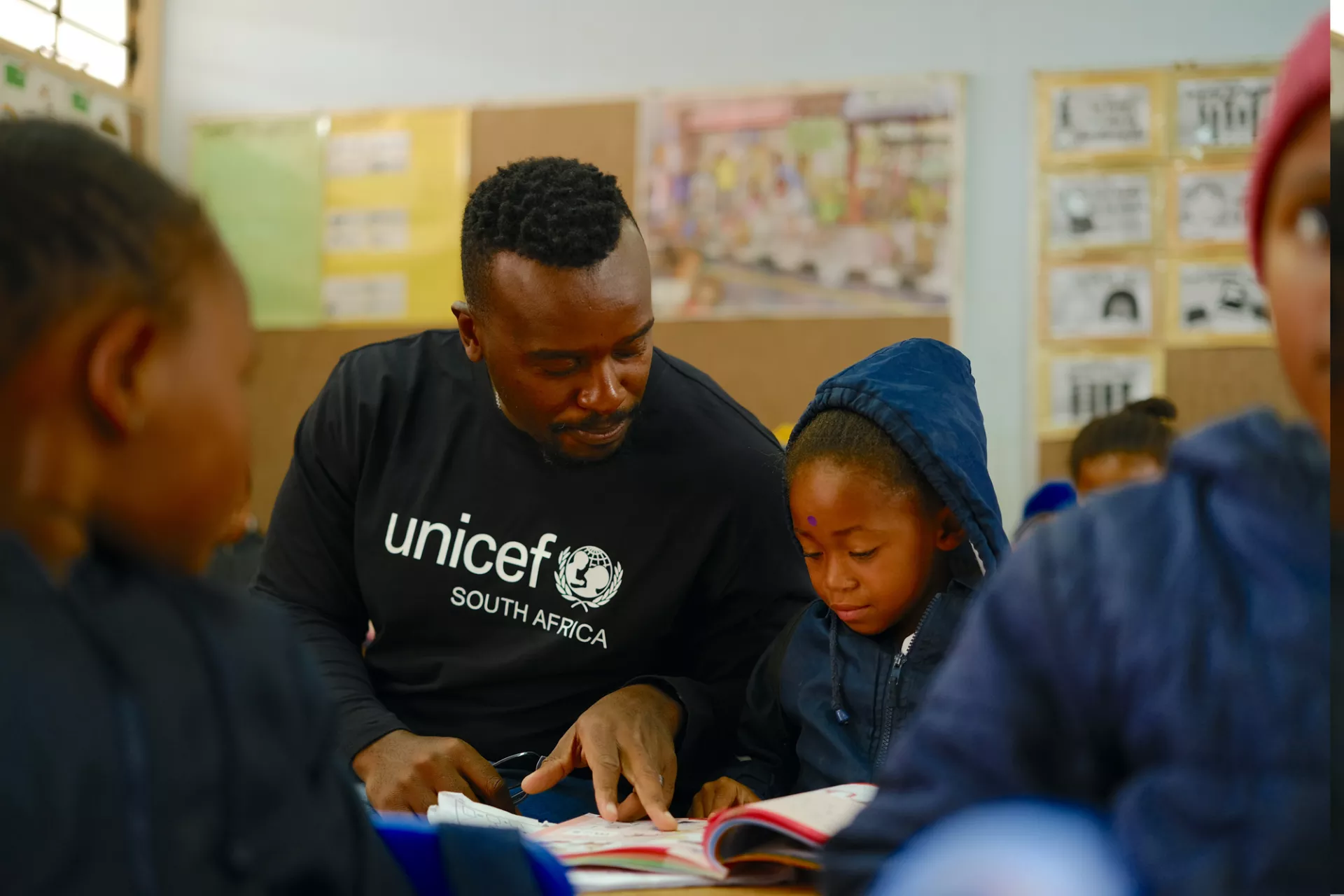 UNICEF staff member helping a child read during a school visit.
