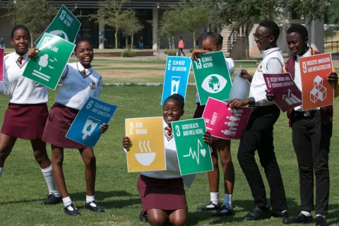 Children in school uniform holding up posters on the Sustainable Development Goals