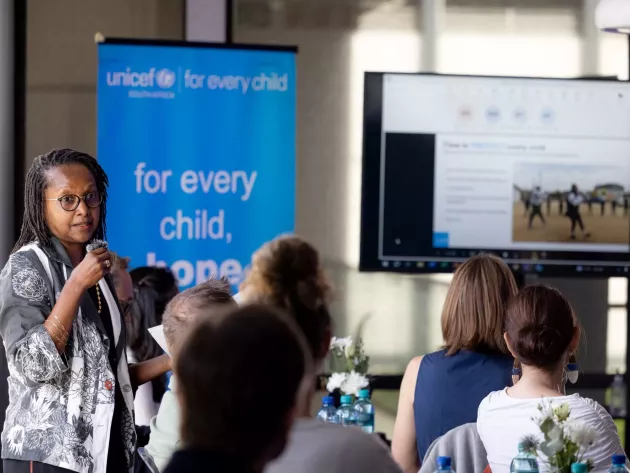 The UNICEF representative addresses a boardroom filled with executives.