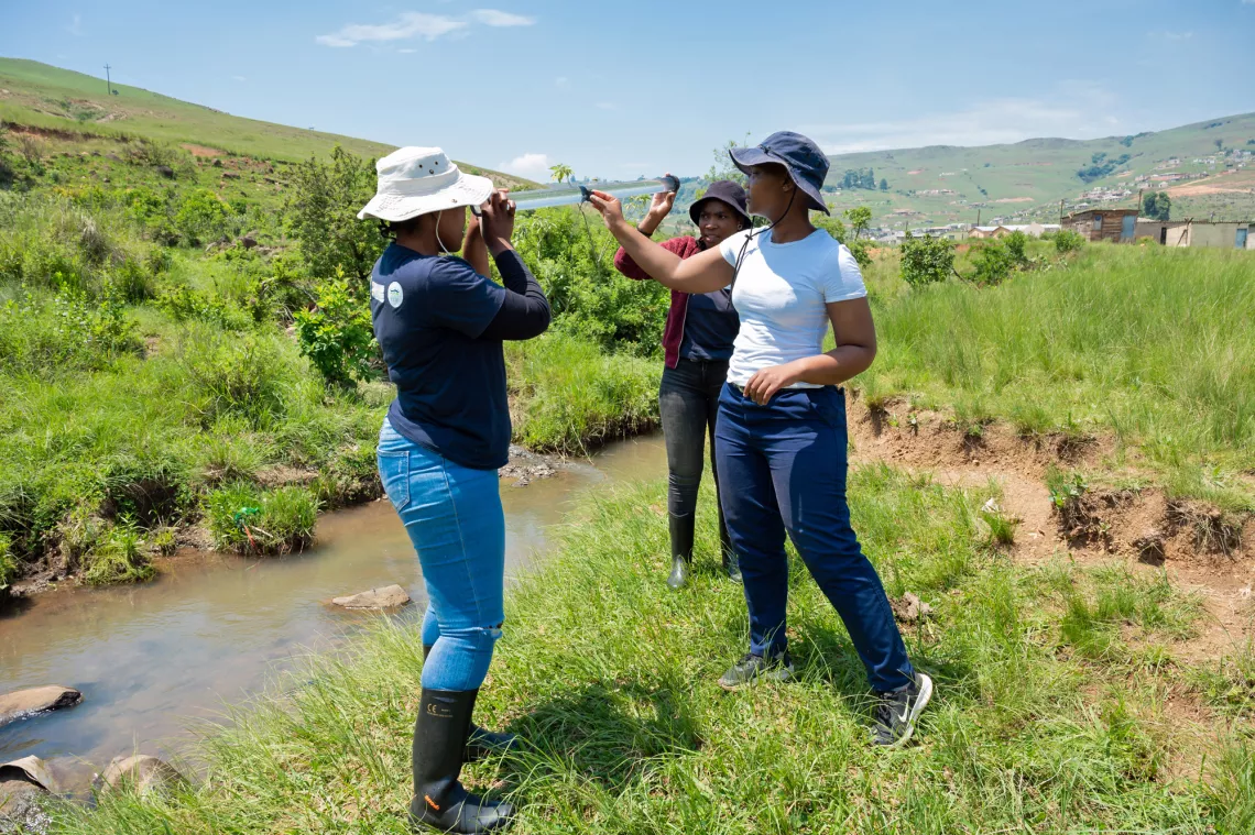 A young women assesses water clarity with her ‘Enviro Champ’ colleagues using part of the ‘mini-SASS’ kit at the Mthinzima stream on the edge of Mpophomeni in KwaZulu-Natal. 