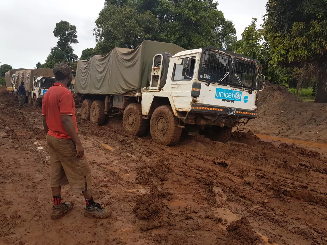 Trucks drive down a muddy road
