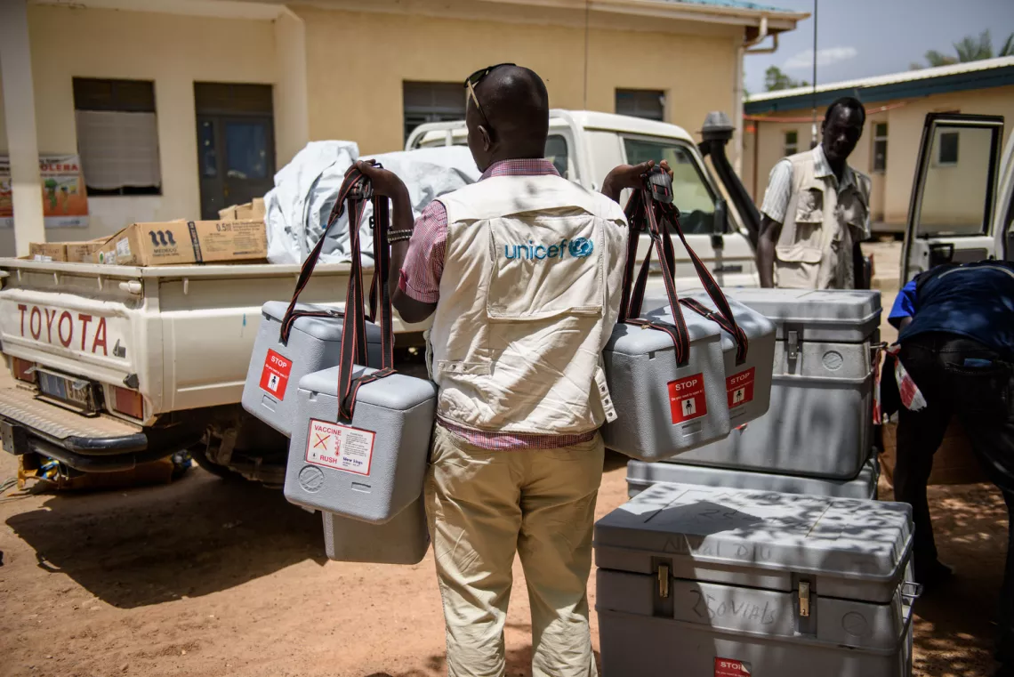 A UNICEF health worker carries cool-boxes containing vaccine