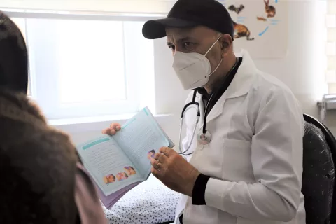 A doctor explaining a card to the person standing next to him