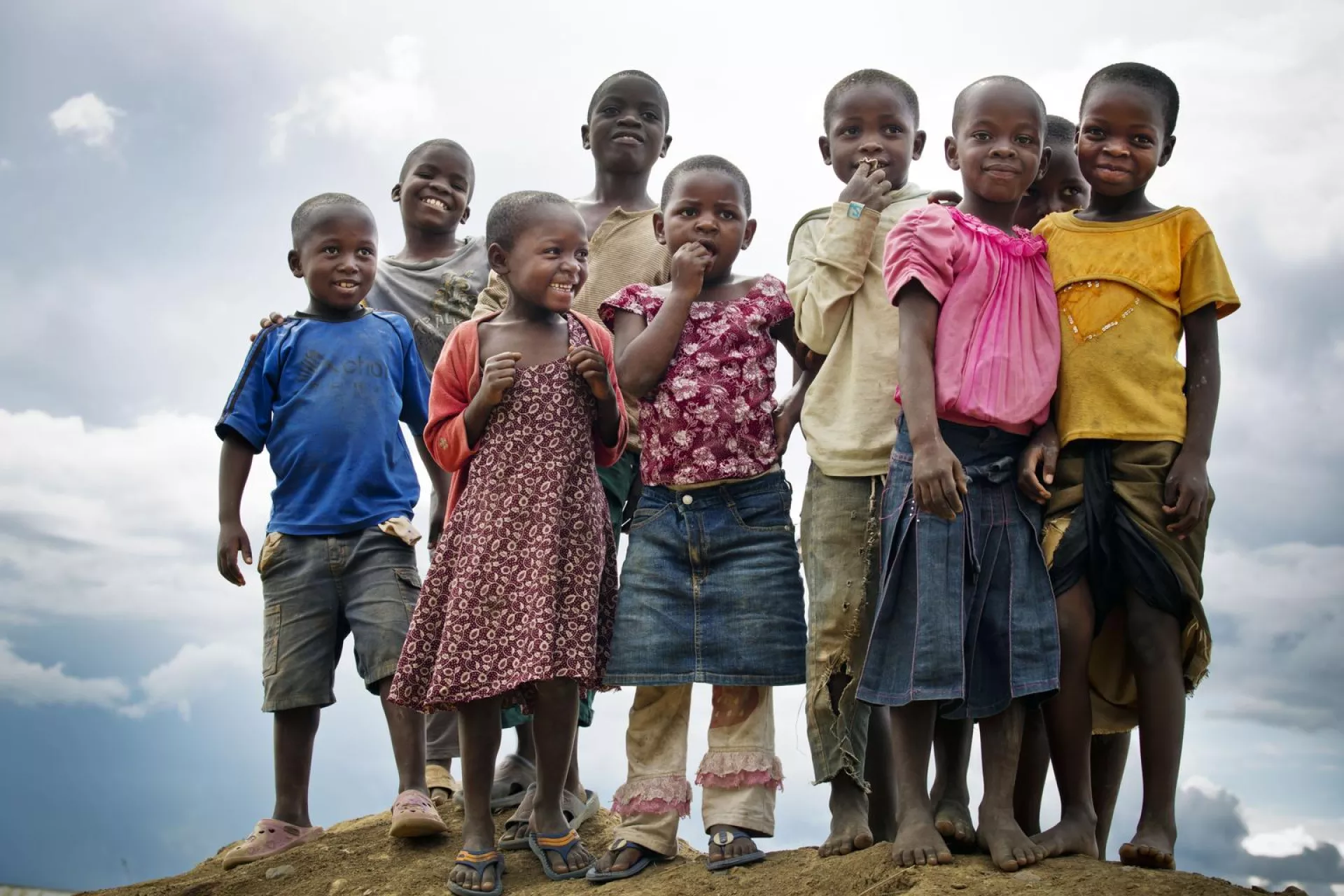 A group of young children stand on a hill and pose for a photograph