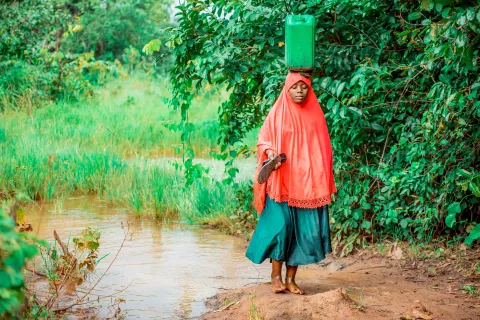 11-year-old Tausi Katambarai balances a 20-liter jerrican of water on her head before walking home at Kaguruka village, Kasulu district, Kigoma Region of Tanzania.
