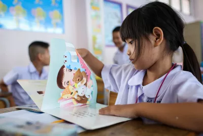 A girl enjoys reading a story book in her classroom.