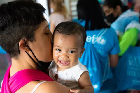 Una madre con su bebé en sus brazos mientras participa en una actividad en un centro de salud apoyado por UNICEF 