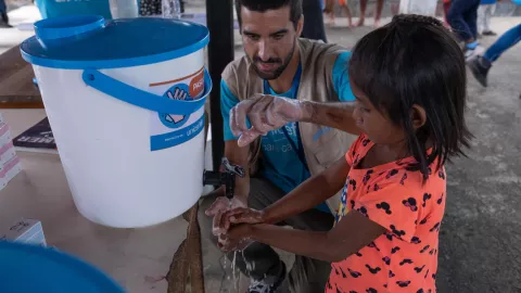 Pedro Ogando, especialista en WASH, muestra a una niña la técnica correcta de lavado de manos en una escuela apoyada por UNICEF ubicada en San Francisco de Guayo en el estado Delta Amacuro.