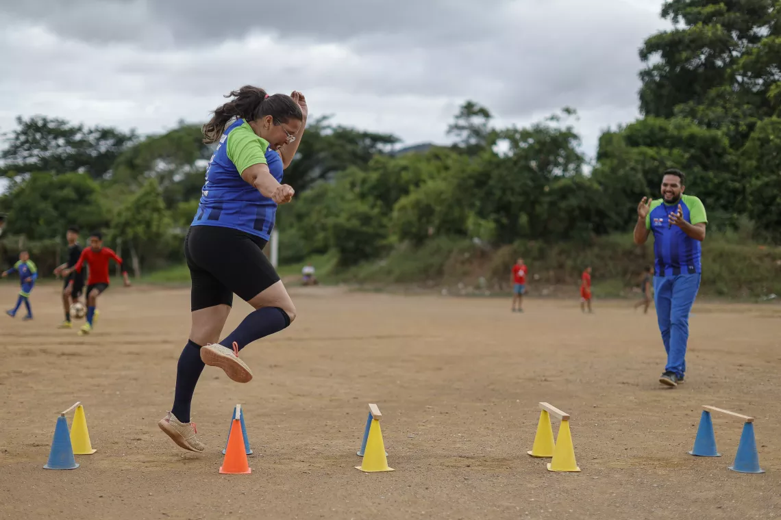 Emma Millán voluntaria de Cáritas Carúpano e integrante del equipo de madres de Misericordia F.C., salta obstáculos mientras el entrenador Robert Rojas la alienta a continuar.