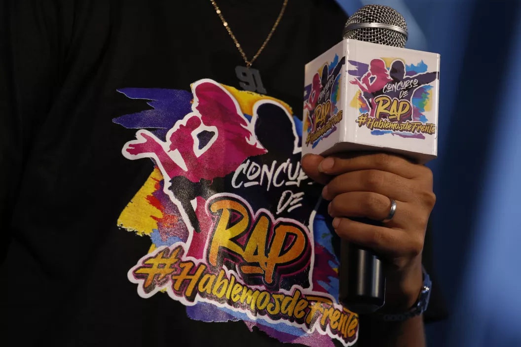 animador del evento de premiación del concurso de rap Hablemos de frente sostiene micrófono mostrando el logotema del concurso