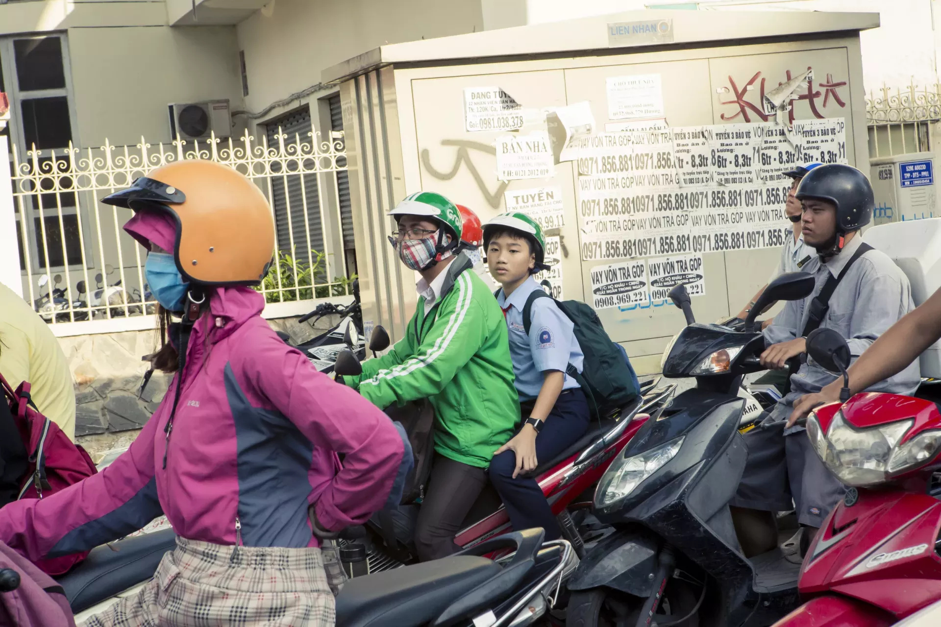 A Grab driver and a boy ride a motorbike on the street