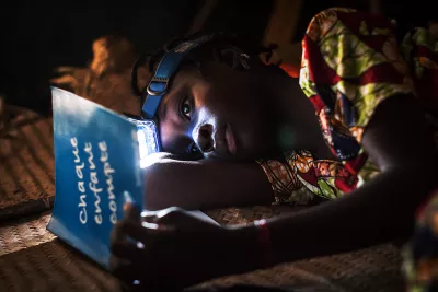 Girl revises her lessons at night using a head lamp