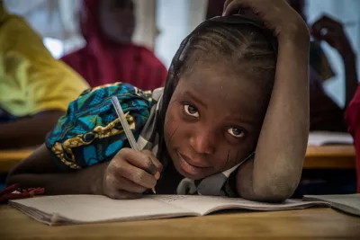 On 17 February, a girl looks up from writing during a class, in a temporary learning space in the Ngagam displacement camp in the Diffa region.