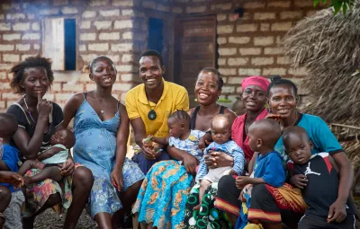 On 30 March, Community Health Worker Osman S. Koroma (centre, in yellow shirt) smiles with women in a mother support group in Kathirie Village in Safroko Limba Chiefdom, Bombali District. 