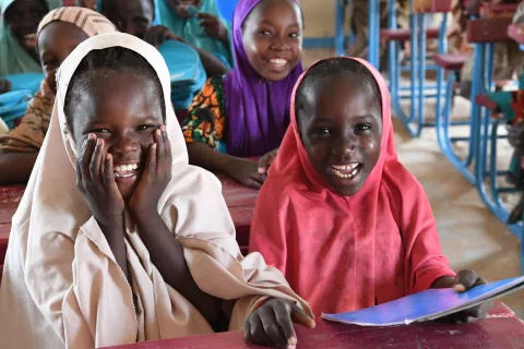 Girls smiling while sitting at their desk in their classroom