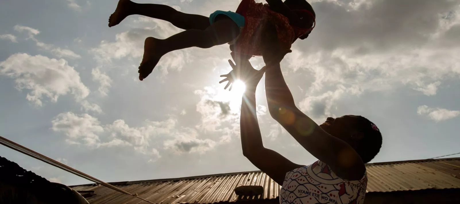 A mother and child playing, photographed against the sky