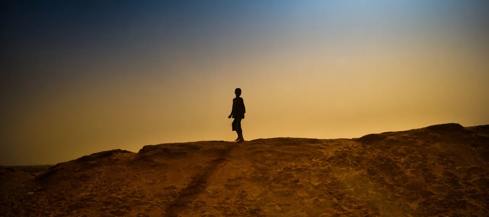  A boy walks on the sand bank surrounding M'Bera refugee camp. 