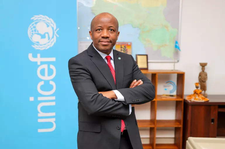 A headshot of UNICEF Regional Director for West and Central Africa, Gilles Fagninou, crossing his arms with a UNICEF logo in the backdrop.