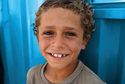 A Syrian boy smiling against a blue background