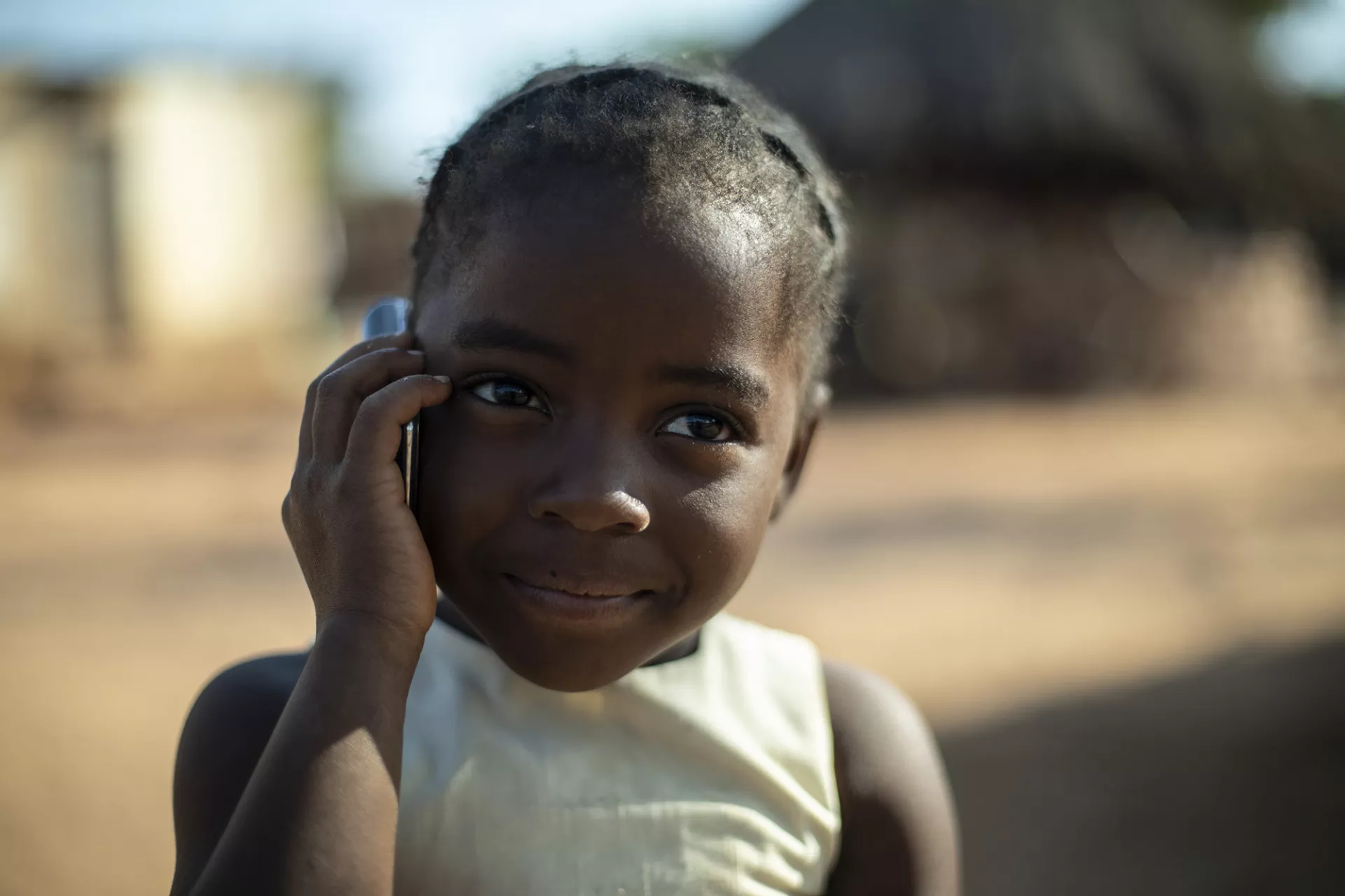 A small girl in a village on the telephone