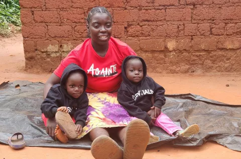 Felister with her twin daughters at home in Mwinilunga