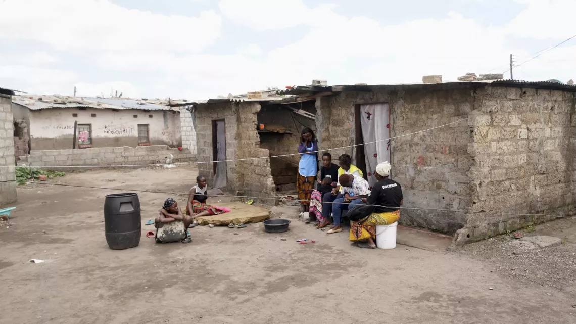 People sitting outside of their home with community health volunteers.