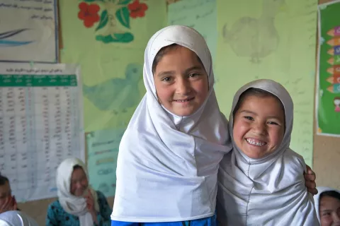 On 1 May 2023, two girls smile inside their Grade 1 classroom in Eskan Village, Nili District, Daikundi Province, Afghanistan.