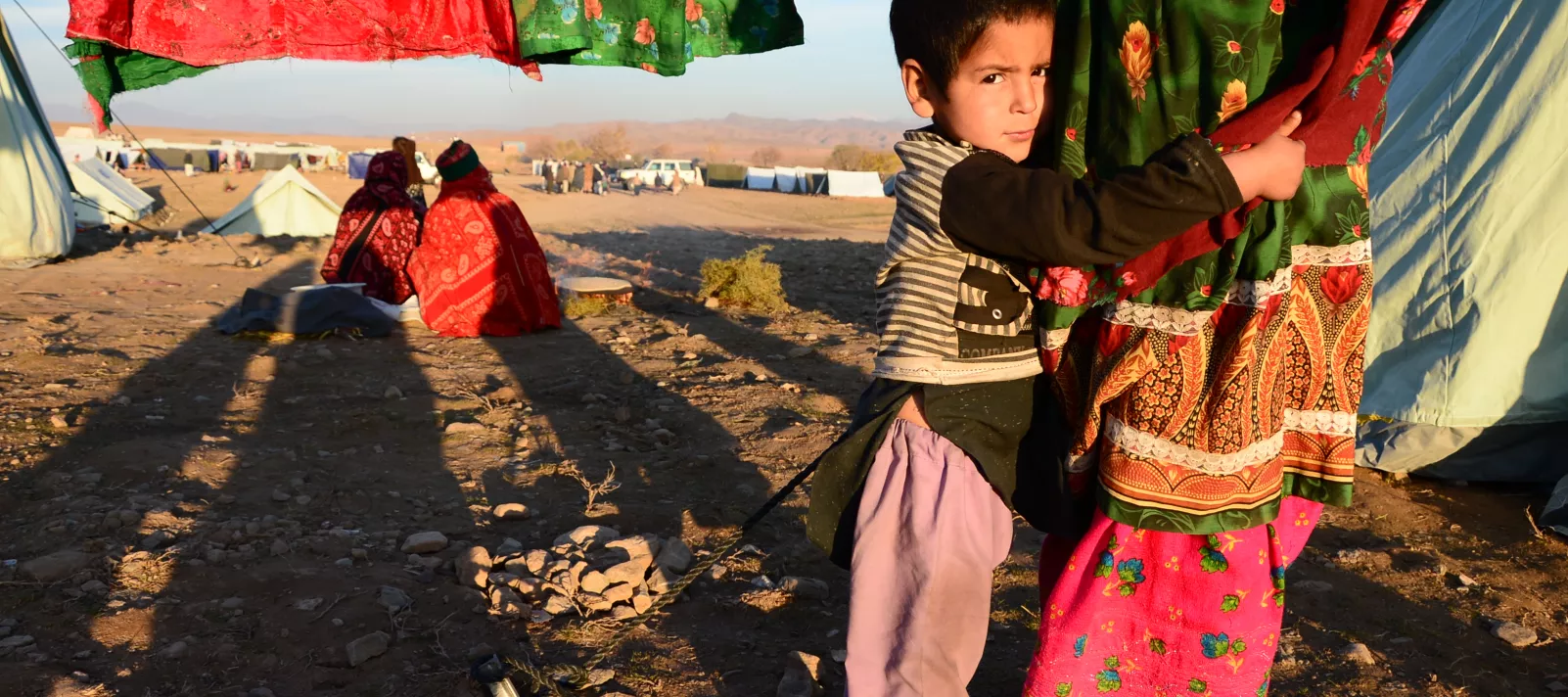 A displaced boy looks on while holding his mother in an IDP camp in Herat province of Afghanistan