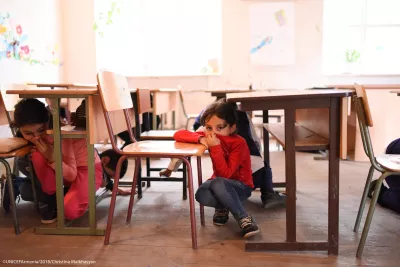 A girl hiding under the table and covering her mouth during the preparedness drills in the school in border village of Nerqin Tsakhkavan. 