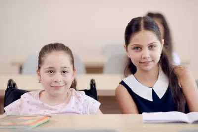 Two girls on their desks in the classroom.