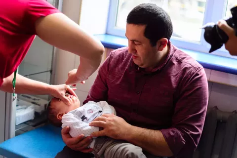 Մինչև մեկ տարեկան երեխան պոլիոմիելիտի դեմ պատվաստում է ստանում. նա հոր գրկին է