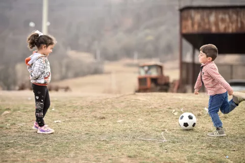 A boy and a girl playing football in a deserted field