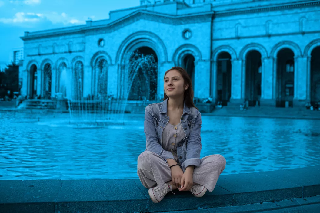 Adolescent girl is sitting in the Republic Square of Armenia. 