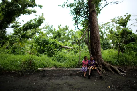 two children sit in a forest in the village of Itaita, Middle Bush, Tanna