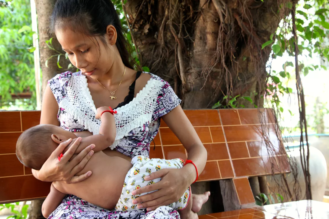 A mother breastfeeds her 6-month-old baby outside the health centre in the village of Preak Krabao, Kang Meas District, Cambodia