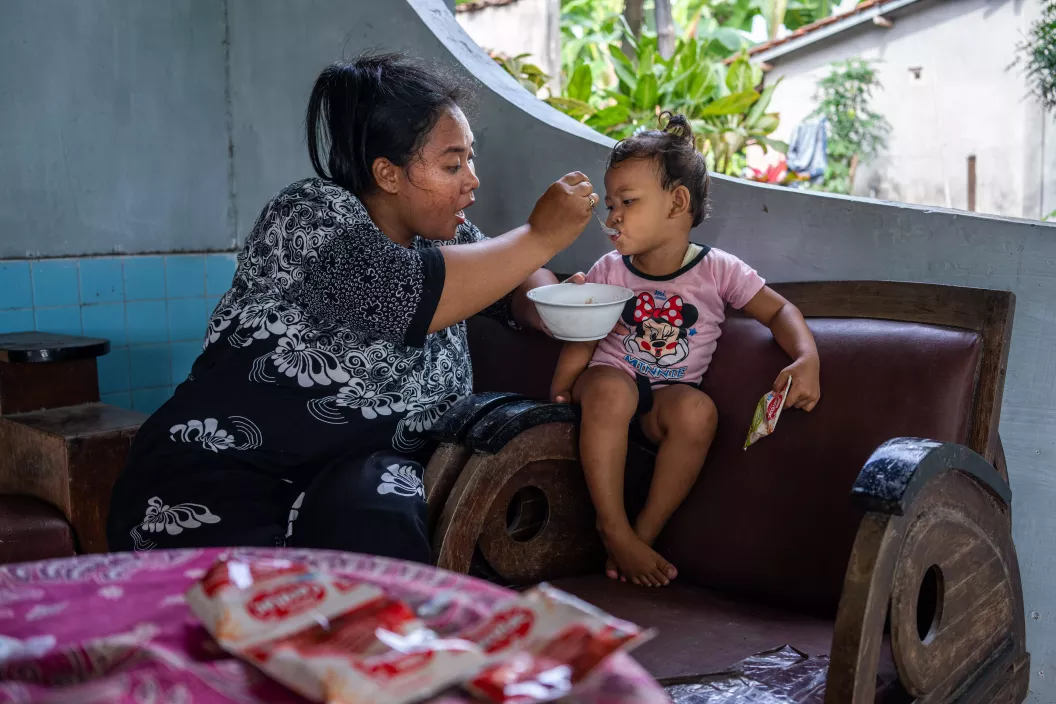 A mother feeds cereal to her daughter (2 years old) at their home